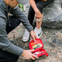 Load image into Gallery viewer, Person using a first aid kit outdoors on a rocky surface